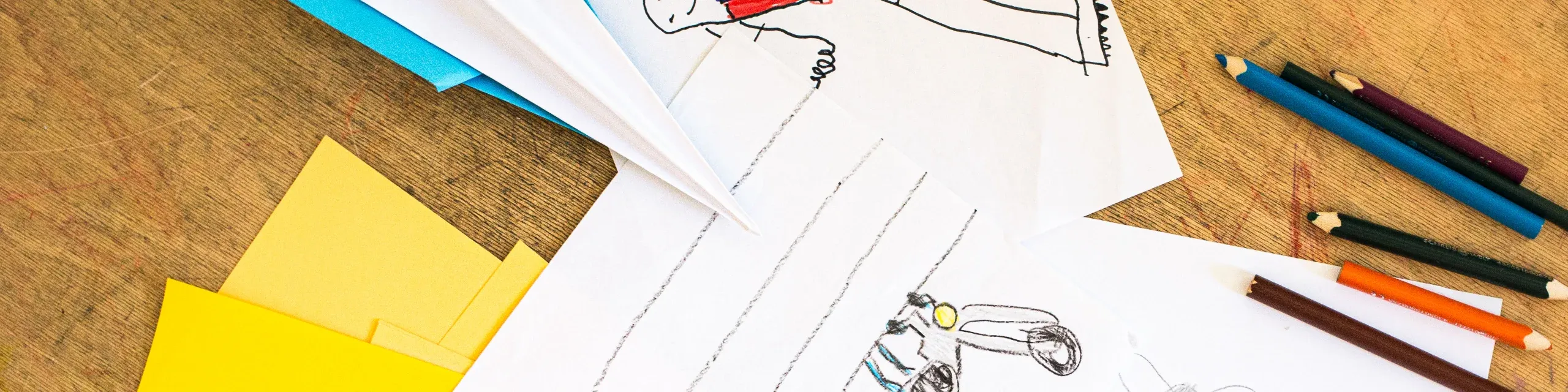 Kinderzeichnungen, Bleistifte und Papierflugzeug